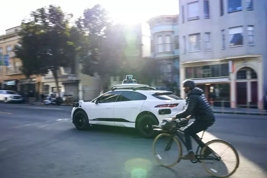 Person, die auf einem Fahrrad hinter einem Waymo-Auto fährt